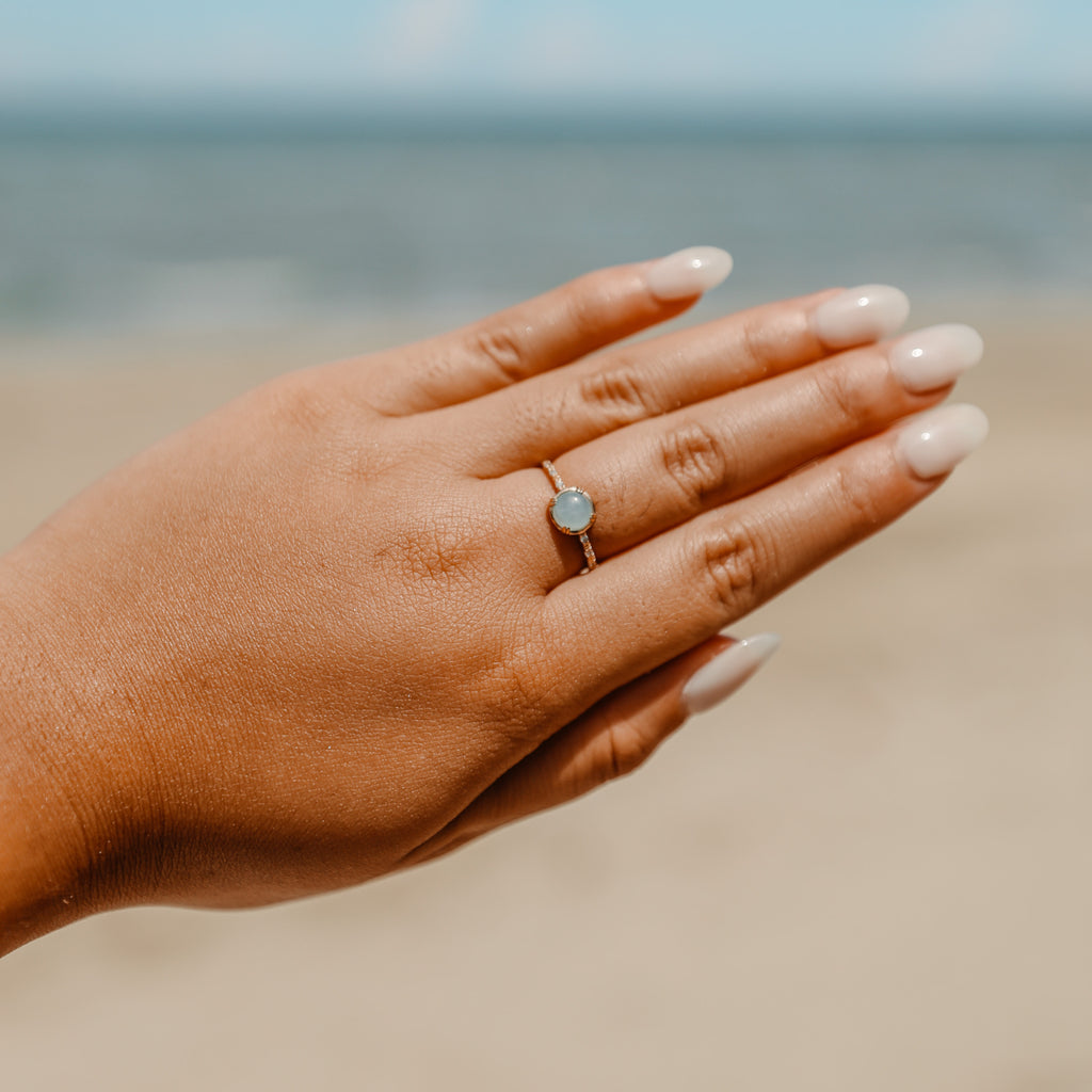Aquamarine stone ring in gold vermeil worn on a hand at the beach