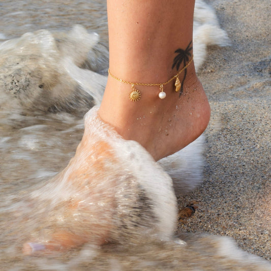 Gold beach anklet with pearl, sun and seashell charms on an ankle