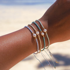 Stack of gold beaded summer bracelets on a wrist