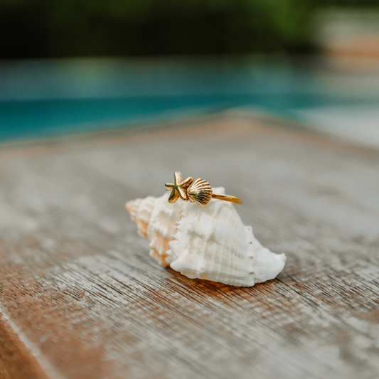 Gold starfish and seashell engraved ring worn on a hand