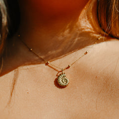 Gold sea snail charm necklace worn at the neck