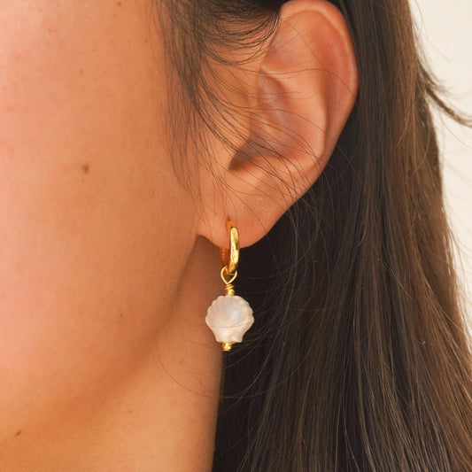 Ceramic seashell charm earring on a gold vermeil hoop worn on the ear