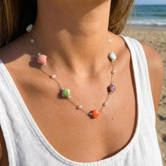 Colorful ceramic shell charm necklace on a gold chain worn at the neck