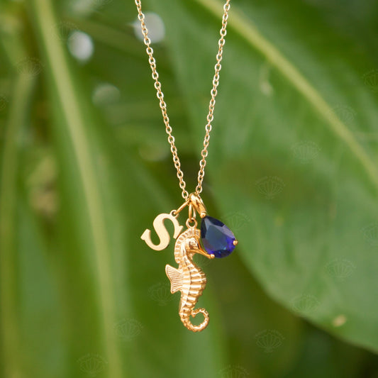 Gold seahorse charm necklace with an initial and birthstone worn at the neck