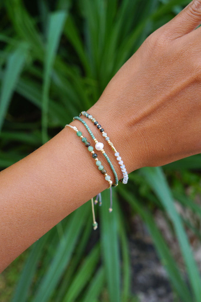 Stack of green beaded surfer bracelets on a wrist