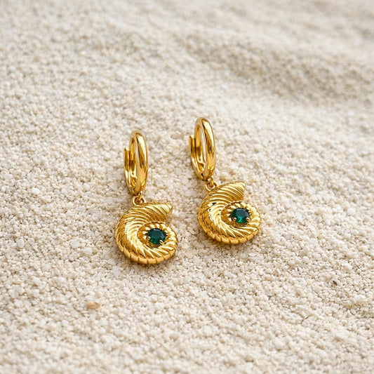 Gold seashell charm hoop earring with a green gemstone worn on the ear