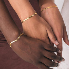 Gold herringbone chain bracelet worn on a wrist