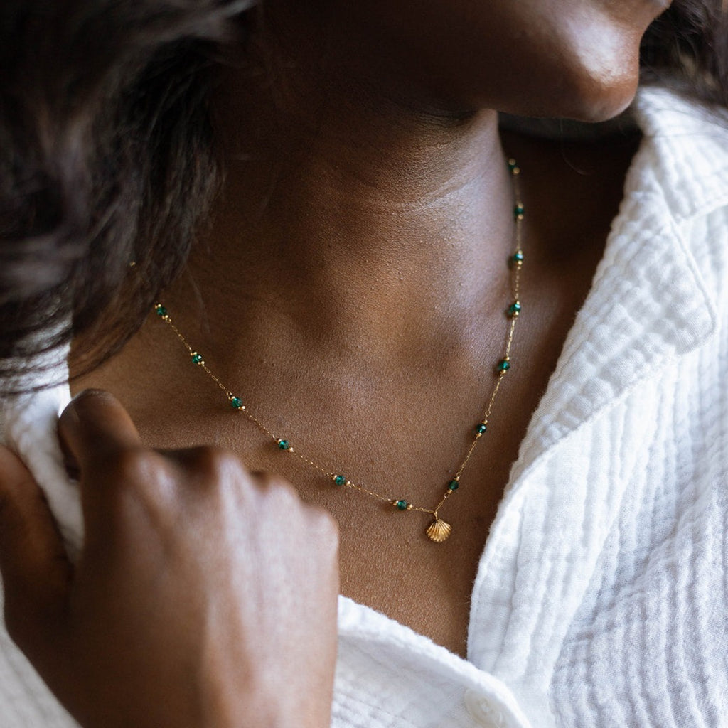 Gold paperclip chain necklace with green glass beads worn at the neck