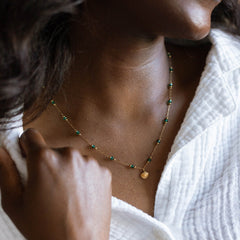 Gold paperclip chain necklace with green glass beads worn at the neck